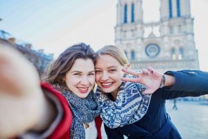 girls taking selfie in Paris at the Notre Dame